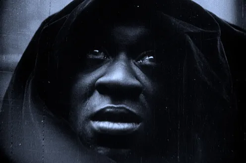 The face of a man covered with a dark hood