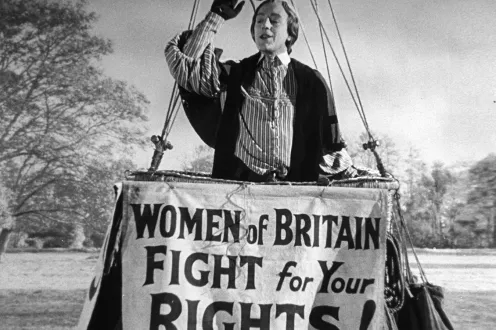 A person in a large basket behind the sign "Women of Britain Fight for your Rights"