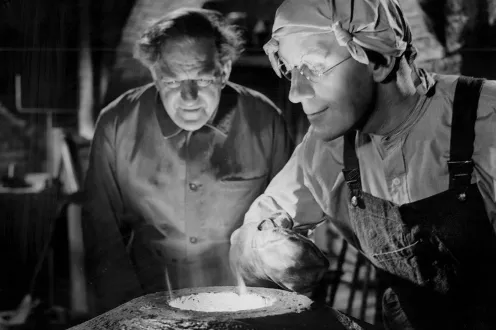 Two people hover over a smelting tool