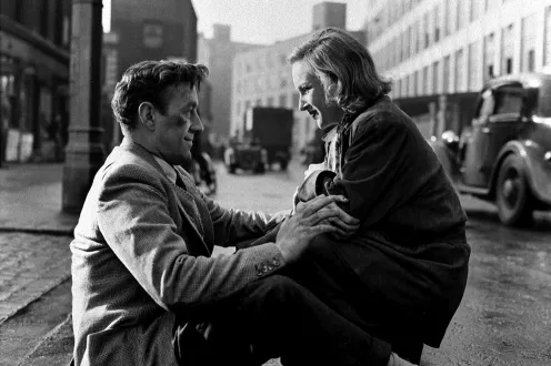 Two people crouch in the street