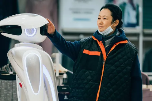 A woman reaching out to a robot