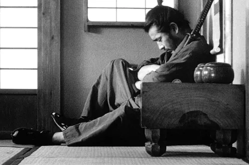 A man sits on the ground hugging a sword