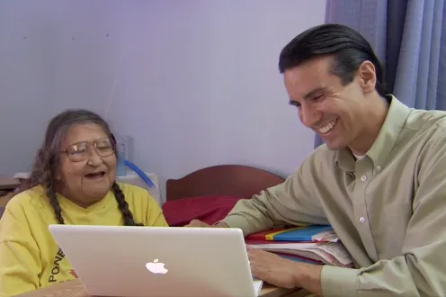Two people smiling and using a macbook