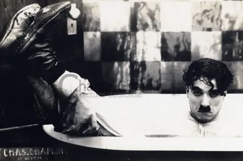 Charlie Chaplin pictured in a bathtub, fully clothed