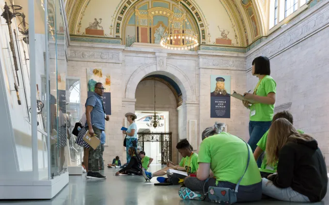 Students on a field trip writing in notebooks in the Great Hall