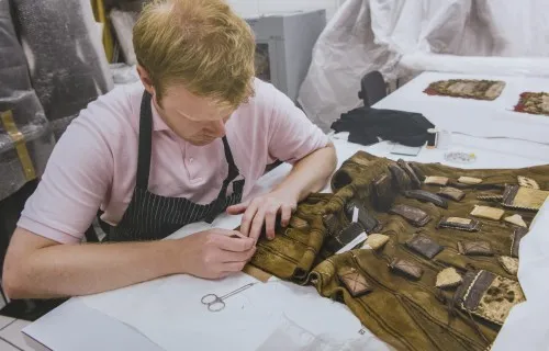 A conservator working delicately on fabric