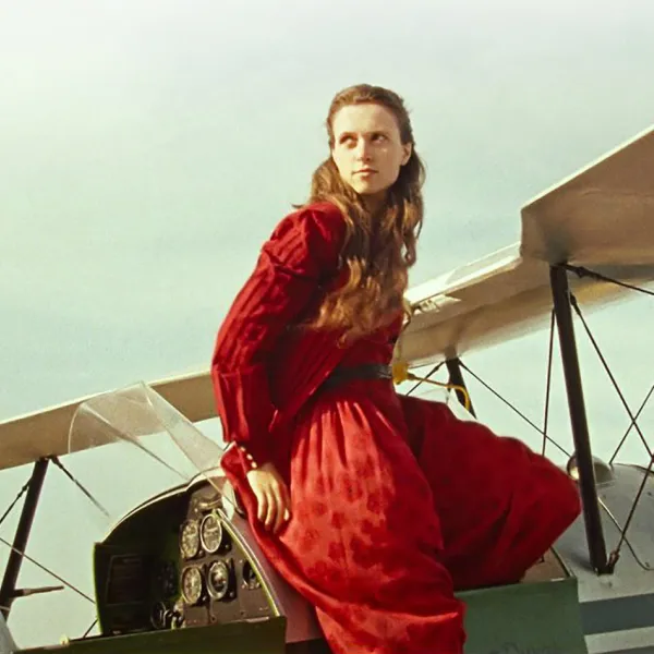 A woman in a red dress sits on a small plane