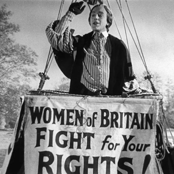 A person in a large basket behind the sign "Women of Britain Fight for your Rights"