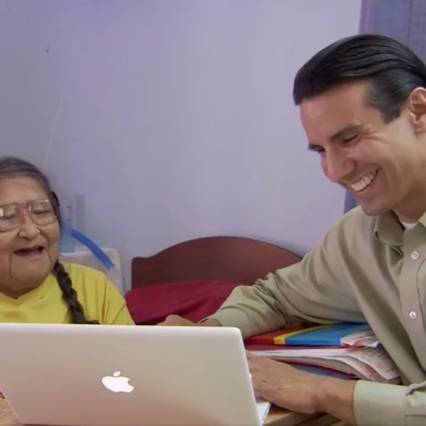 Two people smiling and using a macbook